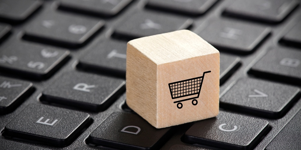 Cubo de madeira com desenho de arrinho de compras sobre um teclado de computador