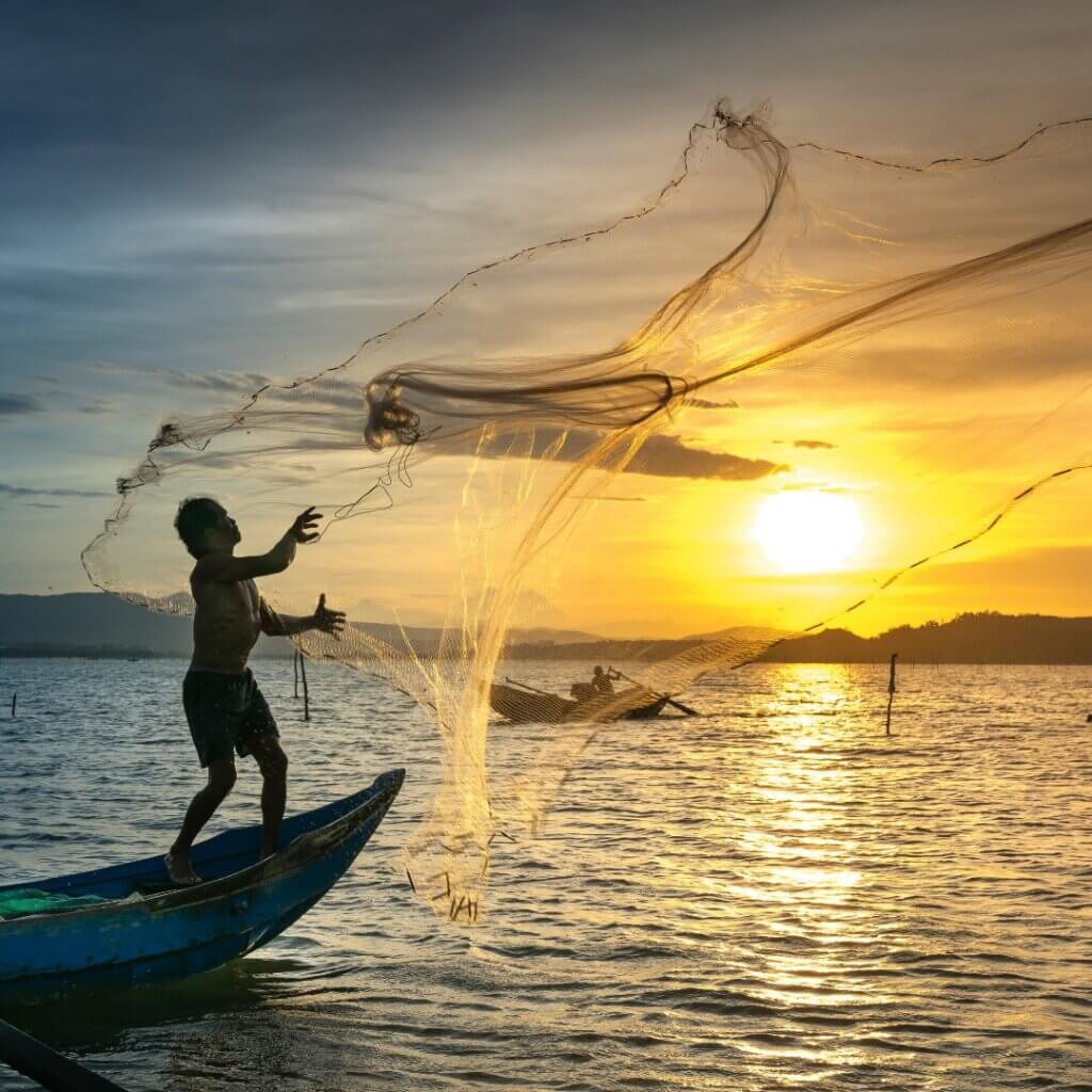 Pescador jogando uma rede de cima de um barco