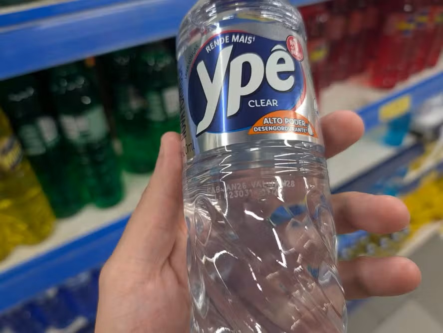 Homem com um detergente Ypê nas mãos
